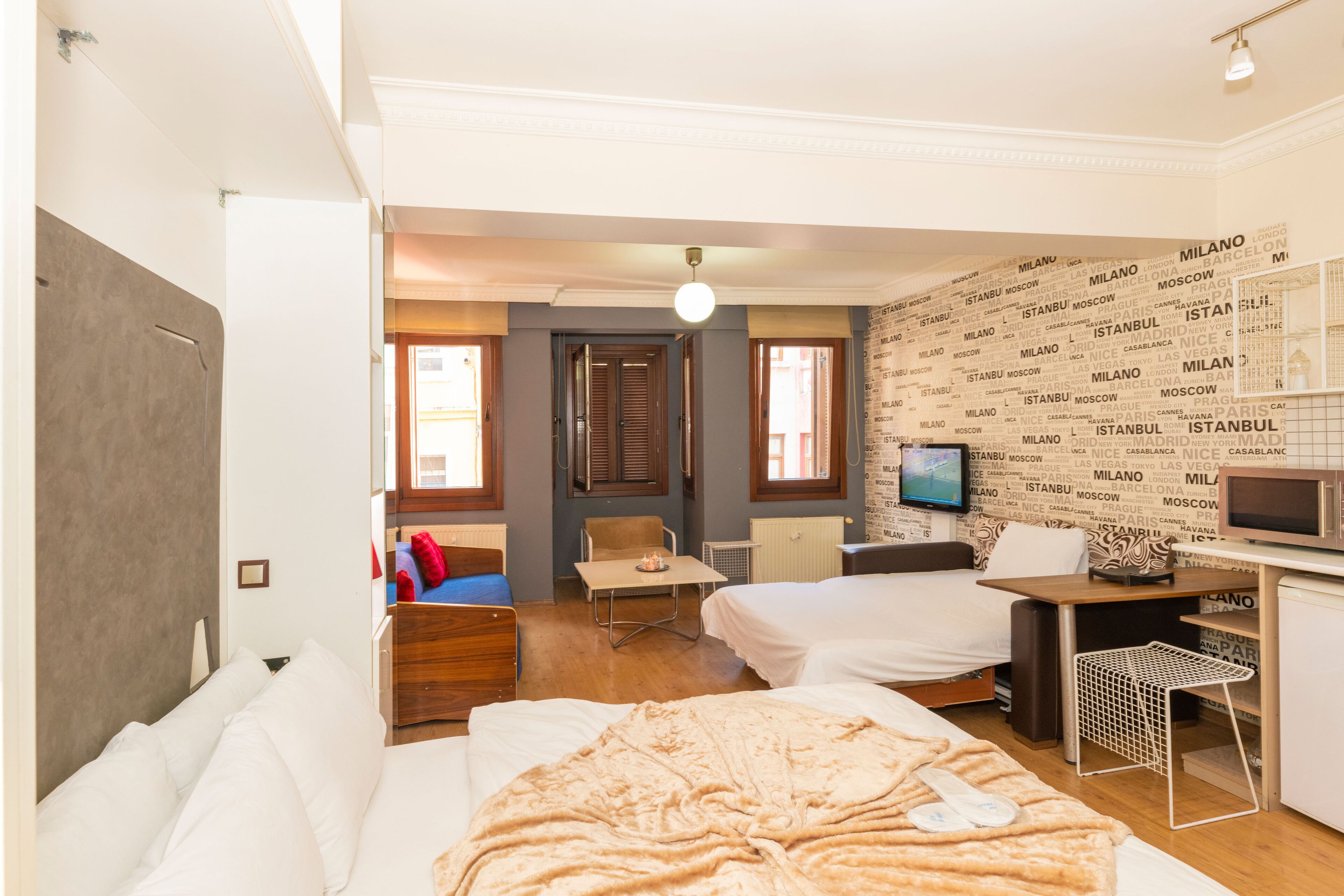 A hotel room with two beds, a desk, a chair, and a television.