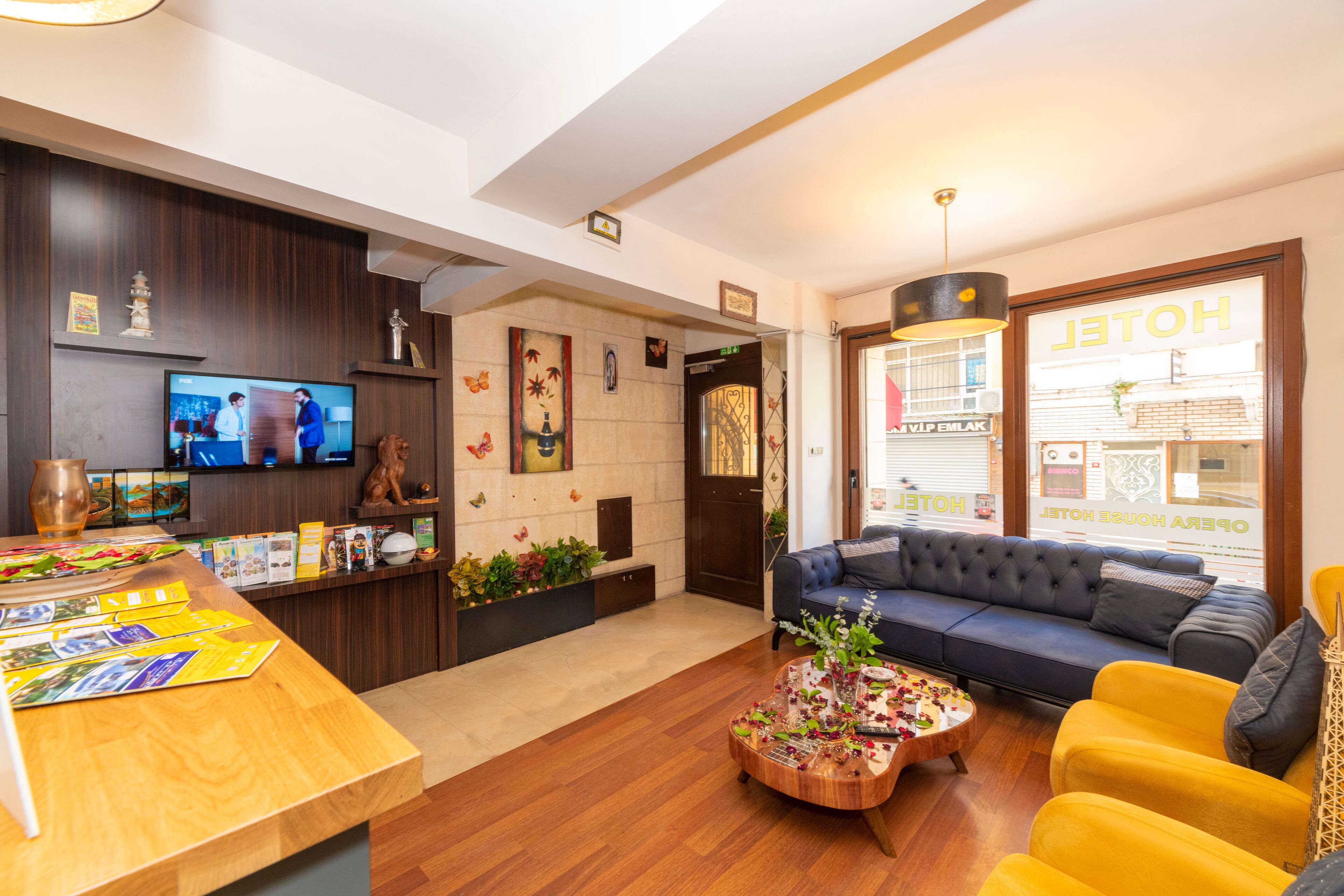 A hotel lobby with a reception desk, a television, a sofa, and a coffee table.