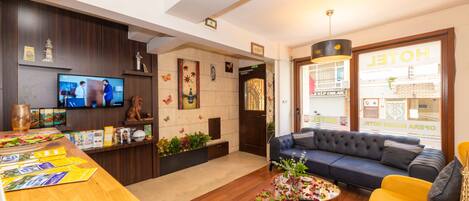 A hotel lobby with a reception desk, a television, a sofa, and a coffee table.
