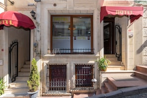 A hotel facade with a double door entrance, a red awning, and a sign indicating "HOTEL" and "OPERA HOUSE HOTEL". - Opera House Hotel (Istanbul)