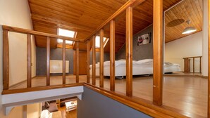 A spacious attic bedroom with a sloped ceiling, wooden beams, a large window, and a view of the adjacent room. - Opera House Hotel (Istanbul)