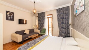 A hotel room with a bed, a sofa, a TV, and a window with curtains. - Opera House Hotel (Istanbul)