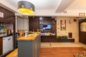 A modern kitchen with a wooden counter, a television, and a coffee machine. - Opera House Hotel (Istanbul)
