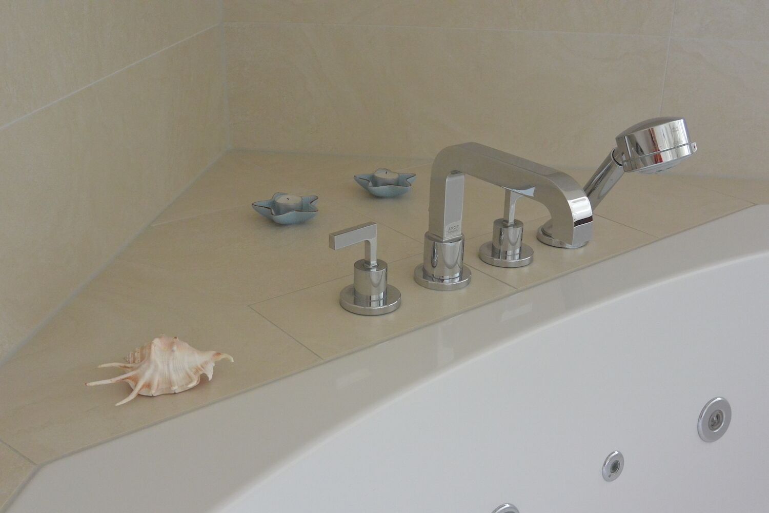 A bathroom with a bathtub, a handheld showerhead, a wall-mounted faucet, and two small bowls on the floor.