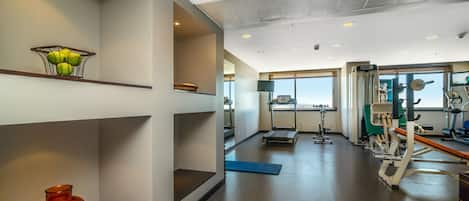 Ein Fitnessstudio mit Trainingsgeräten, Laufband und großem Fenster.