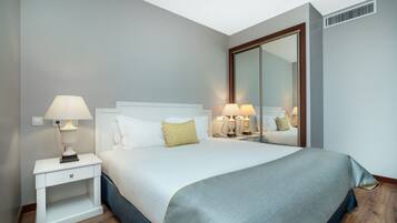 Una camera d'albergo ordinata con un letto grande, due comodini con lampade, uno specchio e un armadio.