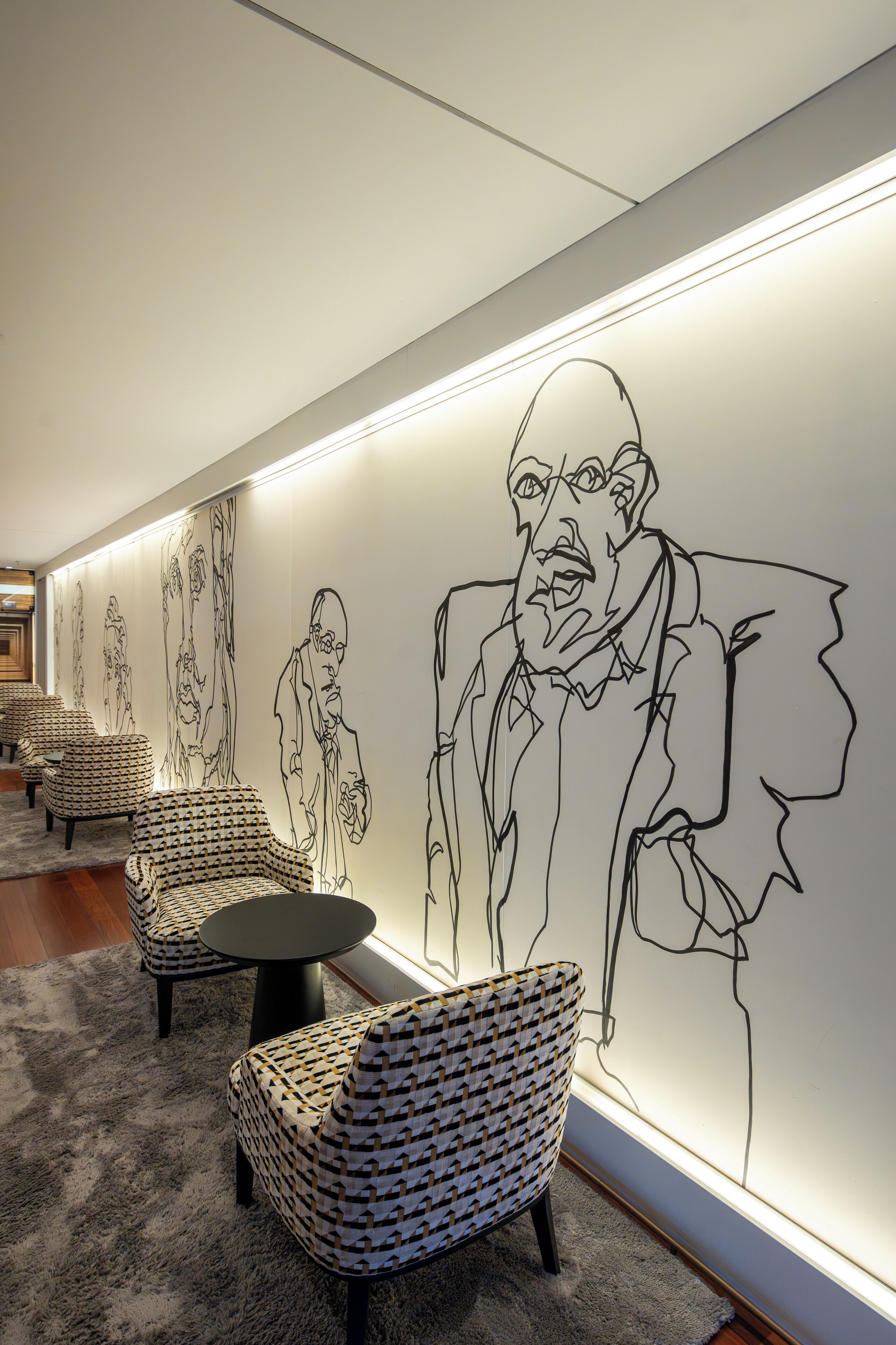 Un interior moderno con sillas estampadas, una mesa redonda y un mural grande en la pared.