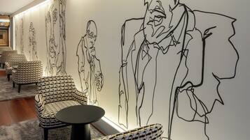 Un interior moderno con sillas estampadas, una mesa redonda y un mural grande en la pared.