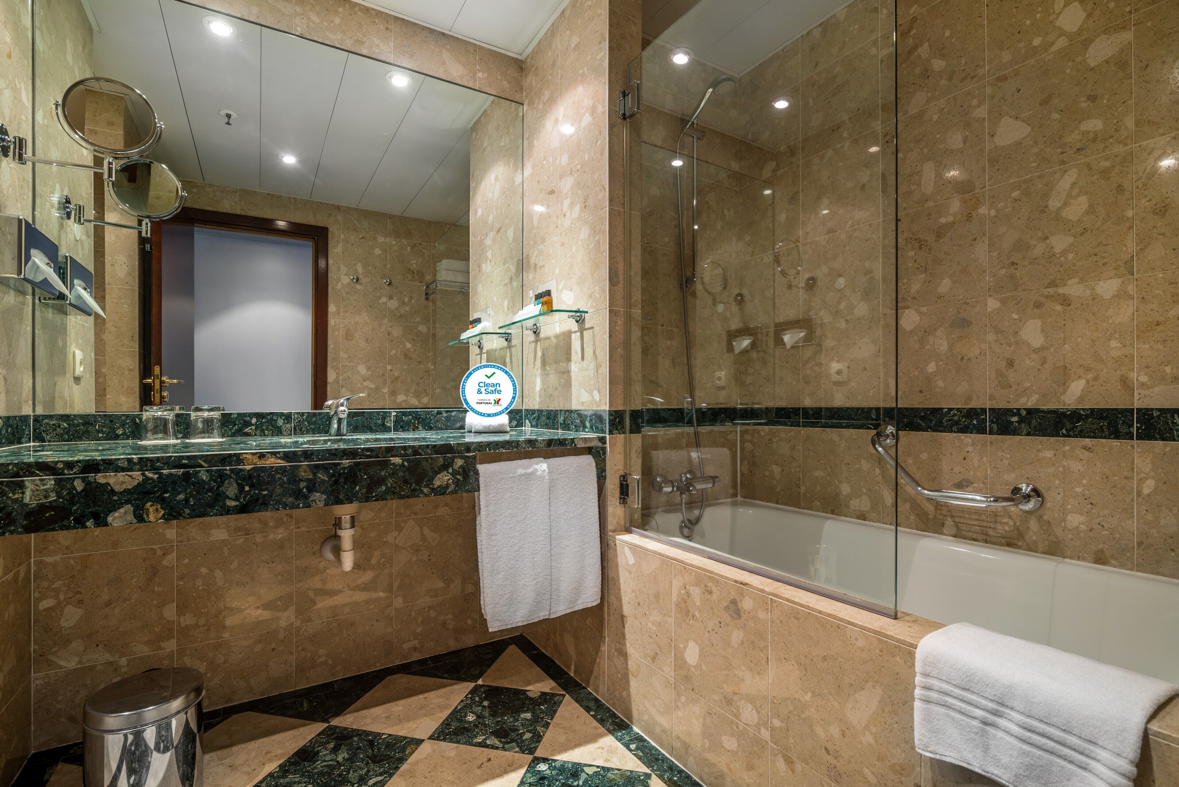 Une salle de bain moderne dotée d’une douche à parois de verre, d’une baignoire et d’un meuble-lavabo en marbre avec un évier et un miroir.