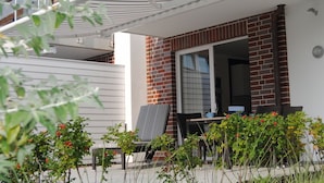 A balcony with a table and chairs, a window, and a white awning. - Baltic Sea Lodges, Deck 1, elevator, wellness area, close to the beach, family friendly (Niendorf)