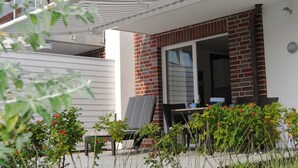 Une terrasse avec des meubles d’extérieur, un mur en briques et une porte-fenêtre coulissante.