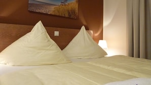 Une chambre d’hôtel avec un lit, des oreillers, un tableau au mur et une lampe.