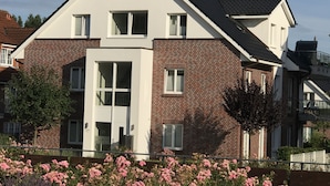 Une maison à deux étages avec une façade en briques et des éléments décoratifs blancs, dotée d’une entrée centrale et de nombreuses fenêtres.