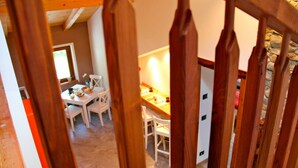 A wooden staircase with a view of a dining area with white chairs and a table. - B&B Il Mortirolo (Mazzo di Valtellina)