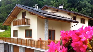 A two-story house with a balcony, stone foundation, and wooden doors. - B&B Il Mortirolo (Mazzo di Valtellina)
