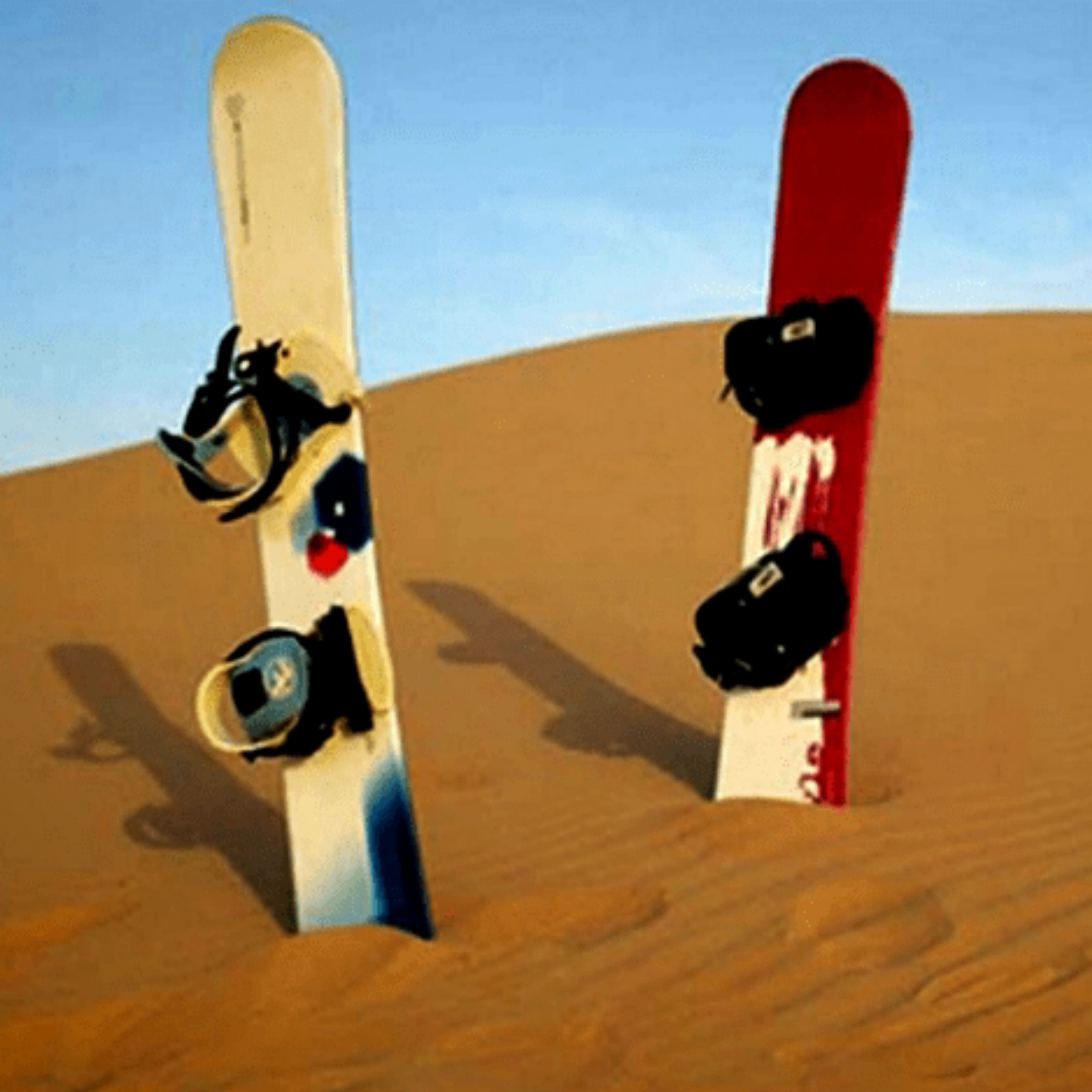 Dos tablas de snowboard apoyadas contra una duna de arena.