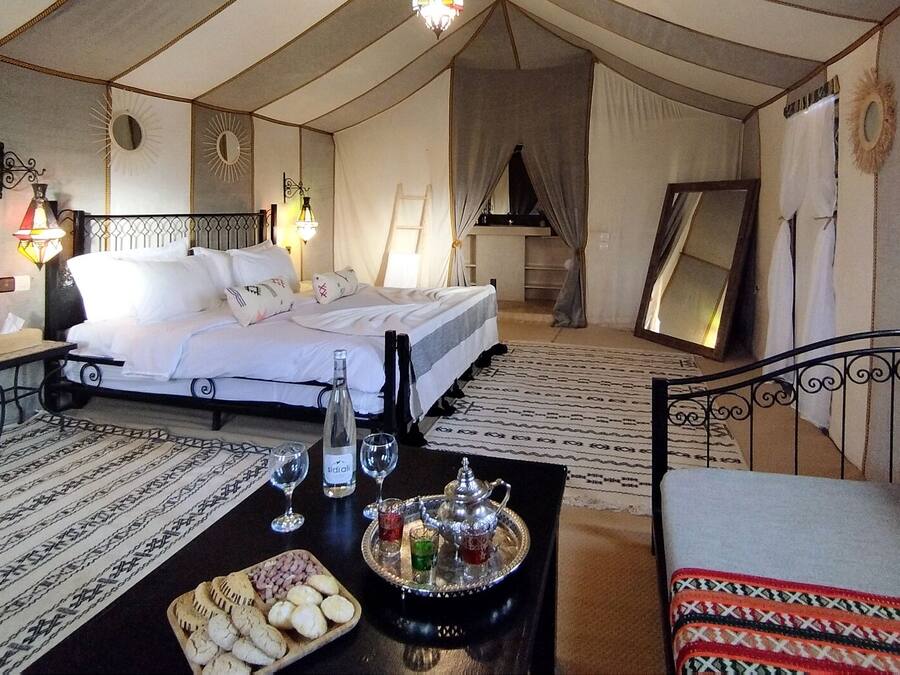 A cozy, well-lit room with a bed, a sofa, and a table with snacks and drinks.
