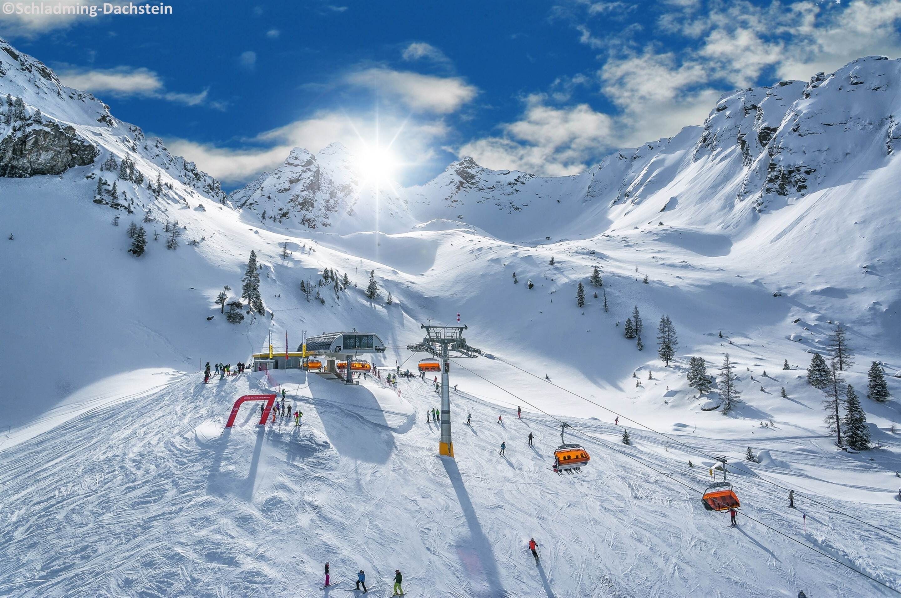 A snow-covered mountain with a ski lift and skiers.