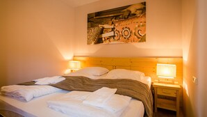 A neatly made bed with white linens and a brown striped blanket, two bedside lamps, and a wooden headboard. - Cozy Apartment near Ski Area in Turracherhohe (Stadl-Predlitz)