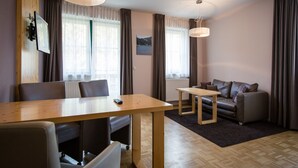 A modern living room with a wooden dining table, a sofa, and two pendant lights. - Studio Apartment on Turracherhohe Near Lake (Stadl-Predlitz)