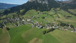 An aerial view of a small village with houses spread across green fields, surrounded by forested hills and mountains in the background. - Schladming Spacious Base With Sauna (Schladming)