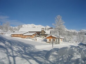 A snow-covered lodge with a large wooden building, a smaller annex, and a mountain backdrop. - Schladming Spacious Base With Sauna (Schladming)