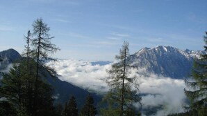 A mountain landscape with snow-capped peaks, dense forest, and a layer of clouds below. - Schladming Spacious Base With Sauna (Schladming)