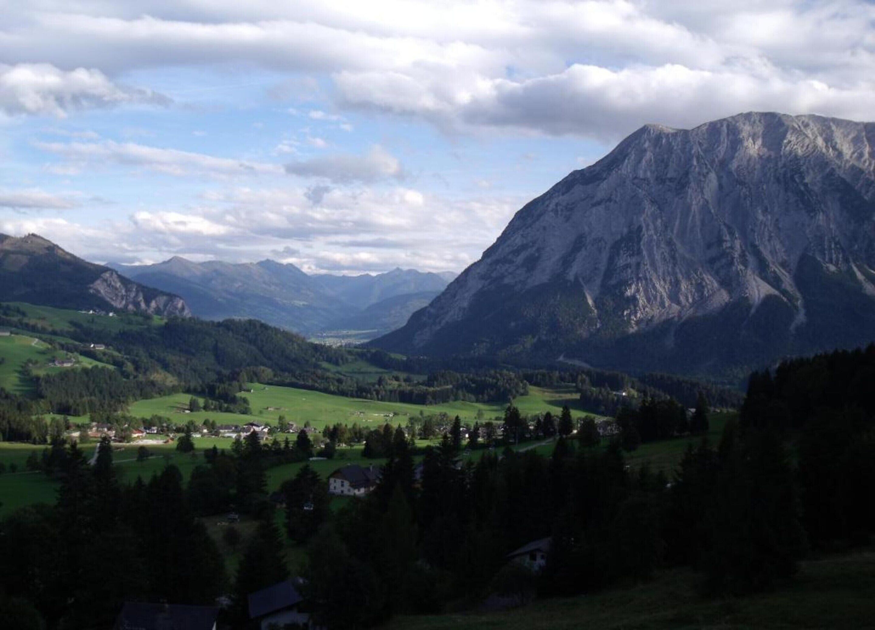 A mountainous landscape with a valley, houses, and a prominent mountain peak.