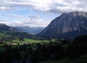 A mountainous landscape with a valley, houses, and a prominent mountain peak.