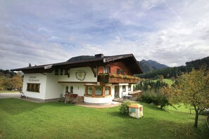 Il s'agit d'un bâtiment de style chalet traditionnel, doté d'un grand balcon, d'un banc en pierre et d'un petit jardin.