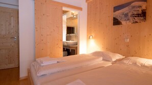 Ein Zimmer mit zwei Betten, Holzwänden, einem Badezimmer mit Waschbecken und einem Bild an der Wand.