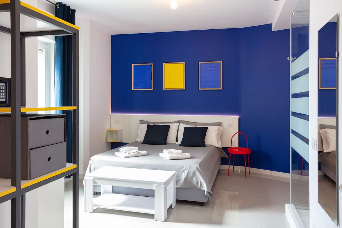 A modern bedroom with a bed, bedside table, and a red chair.
