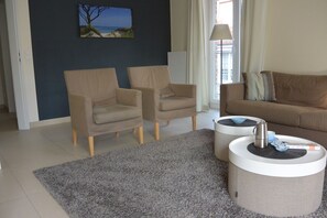 A living room with two armchairs, a sofa, a coffee table, and a rug. - Baltic Sea lodges, apartment deck 3, wellness with sauna, fitness, elevator (Niendorf)