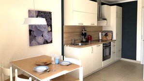 Uma cozinha compacta com armários brancos, bancada de madeira e forno embutido.