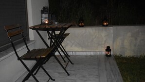 Un patio al aire libre con mesa y sillas, un farol y una pequeña mesa con una vela.