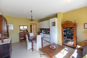 A dining area with a wooden table and chairs, a kitchen with white cabinets, and a display cabinet with glass doors.