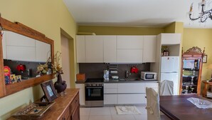 Una cocina con armarios blancos, estufa, microondas y refrigerador.