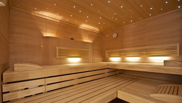 A sauna with wooden benches and slatted walls, equipped with overhead lighting. - Bright apartment with elevator, wellness area, fitness, sauna, families, WiFi (Niendorf)