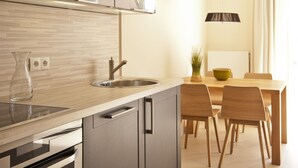 A modern kitchen with a built-in oven, a sink, and a dining area with a table and chairs. - Bright apartment with elevator, wellness area, fitness, sauna, families, WiFi (Niendorf)