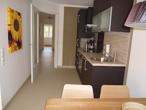 Une cuisine moderne avec des meubles de couleur sombre, des appareils électroménagers en acier inoxydable et un plan de travail en bois.
