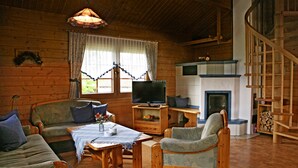 Een gezellig blokhutinterieur met een open haard, houten meubels en een televisie.