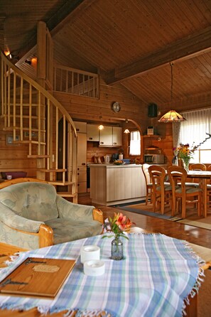A wooden interior with a staircase, a dining area, and a kitchen.