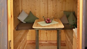 Een houten blokhut van binnen met een tafel, twee banken en een bord waarop 'Lieblichplatz' staat.