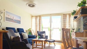Una sala de estar con sofá, sillas, una mesa de centro y un comedor con mesa y sillas.