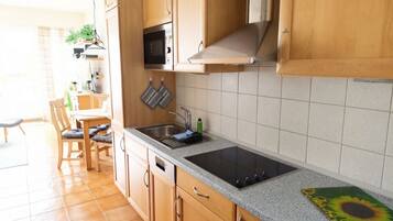 Una cocina con armarios de madera, un microondas, una estufa y un lavaplatos.