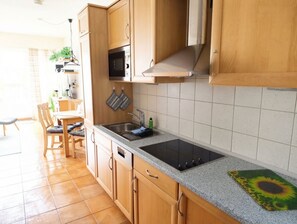 Une cuisine avec des meubles en bois, un four à micro-ondes, une cuisinière et un évier.