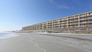 A beachfront hotel with multiple balconies, a sandy beach, and a clear sky. - Stay @ A View to Remember on Folly Beach (Folly Beach)