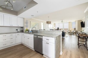 A modern kitchen with white cabinets, a dishwasher, and a marble island. - Stay @ A View to Remember on Folly Beach (Folly Beach)