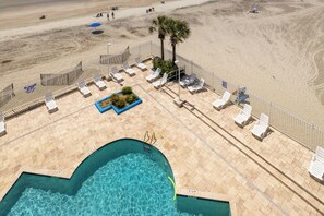 Un espace piscine avec des chaises longues et un panneau indiquant la présence d’un sauveteur.