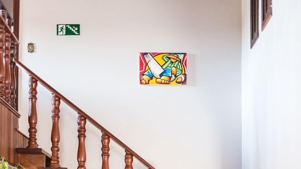 A wooden staircase with a handrail, a round wine rack with hanging bottles, and a vase with a plant. - Sonho Da Serra Pousada (Bento Gonçalves)